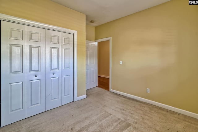 unfurnished bedroom with light carpet and a closet