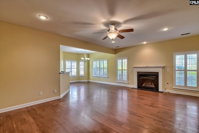 unfurnished living room featuring ceiling fan with notable chandelier and dark wood-type flooring