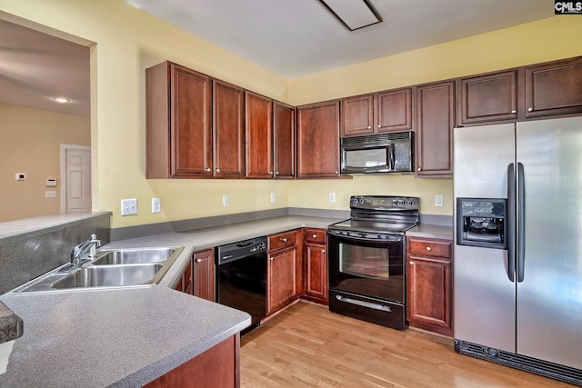 kitchen featuring black appliances, sink, and light hardwood / wood-style flooring