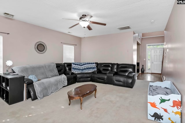 carpeted living room with ceiling fan and a textured ceiling