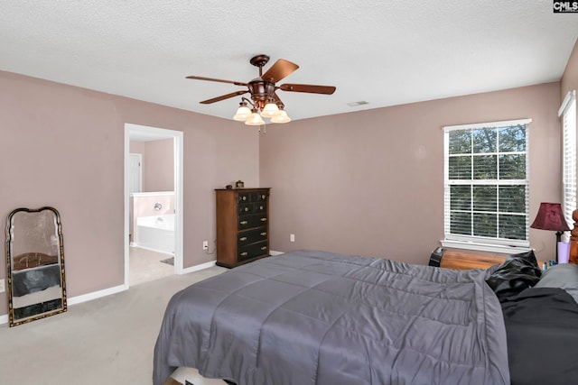 carpeted bedroom with a textured ceiling, ensuite bathroom, and ceiling fan