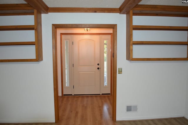 entrance foyer featuring beamed ceiling, a textured ceiling, and light hardwood / wood-style flooring