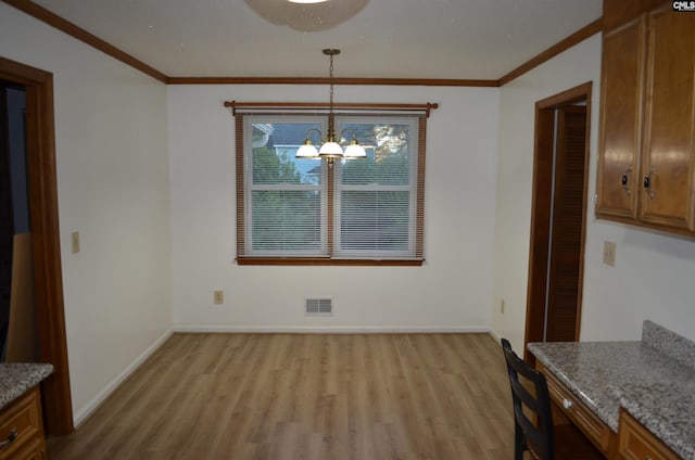 unfurnished dining area with crown molding, a notable chandelier, and light wood-type flooring