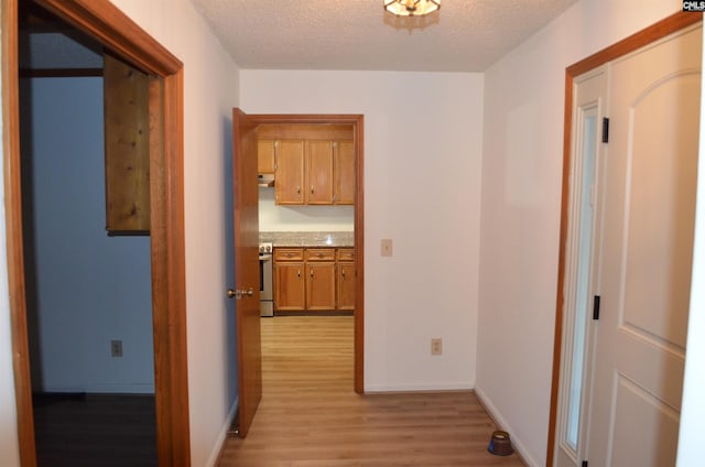 corridor with a textured ceiling and light hardwood / wood-style flooring