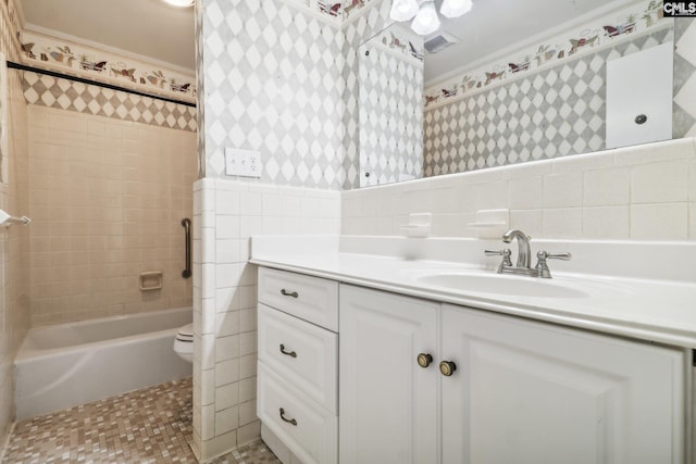 full bathroom featuring ornamental molding, vanity, tiled shower / bath combo, tile walls, and toilet