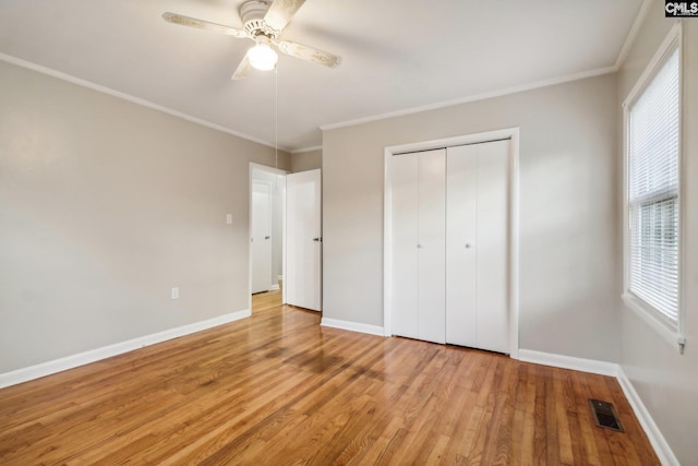 unfurnished bedroom with ceiling fan, light wood-type flooring, crown molding, and a closet