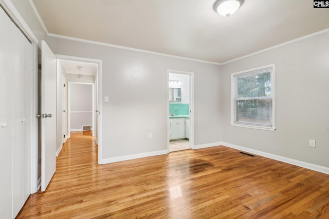 unfurnished bedroom featuring connected bathroom, a closet, light hardwood / wood-style floors, and ornamental molding