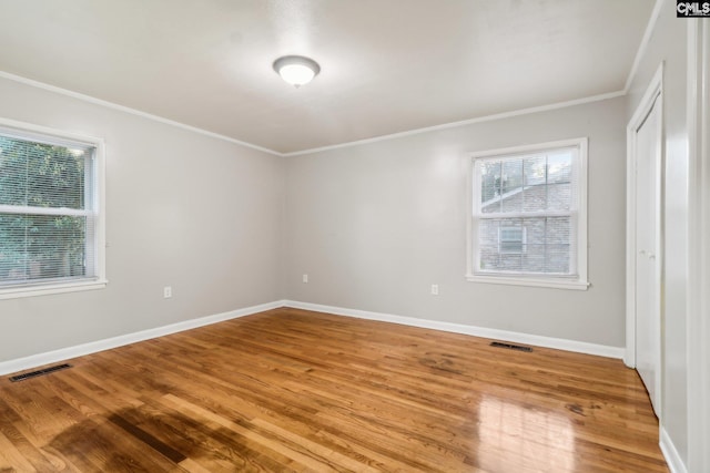 empty room with hardwood / wood-style flooring and crown molding