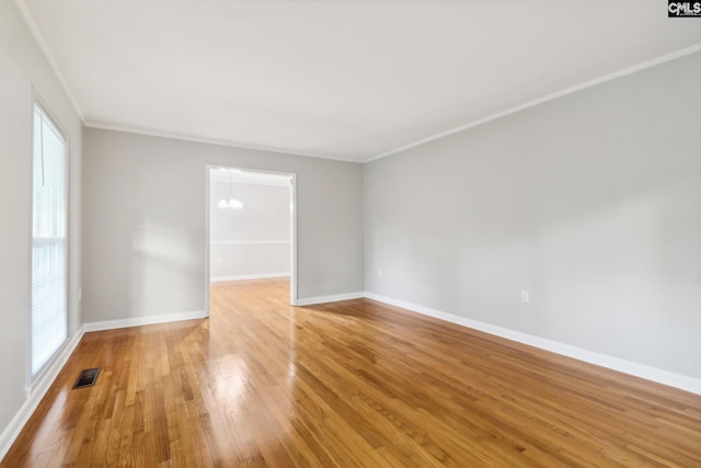 spare room with hardwood / wood-style floors, an inviting chandelier, and ornamental molding