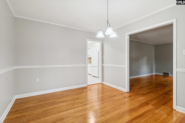 spare room featuring crown molding, a chandelier, and hardwood / wood-style flooring