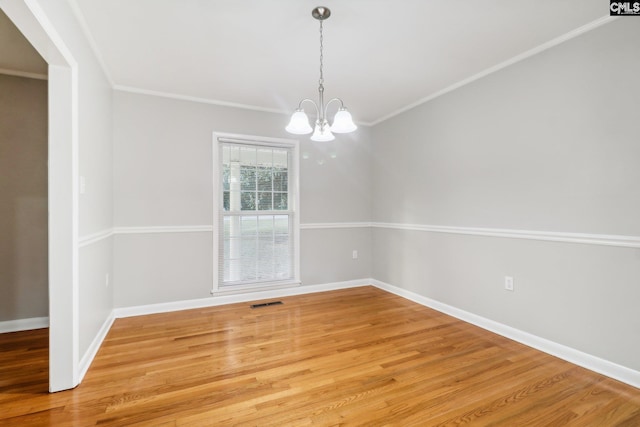 empty room featuring wood-type flooring, crown molding, and a chandelier