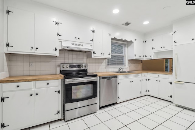 kitchen with white cabinets, appliances with stainless steel finishes, backsplash, and extractor fan