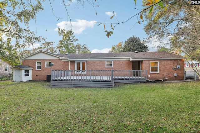 rear view of house featuring a lawn, a wooden deck, and a storage shed