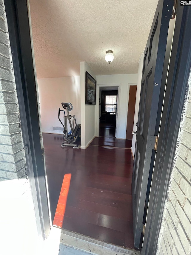 hall featuring a textured ceiling and dark hardwood / wood-style floors