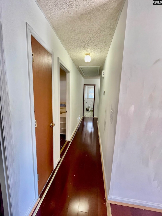 corridor with a textured ceiling and dark hardwood / wood-style floors