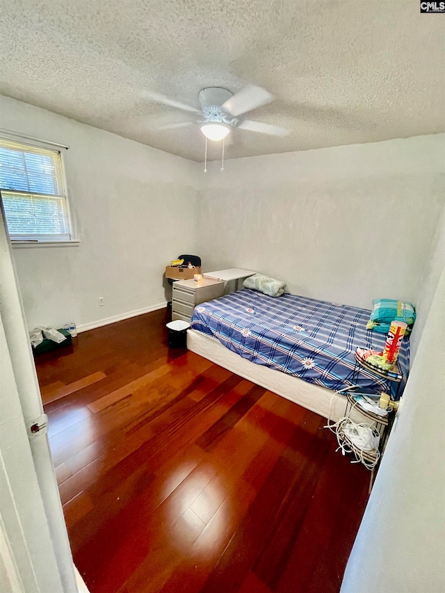 bedroom with a textured ceiling, hardwood / wood-style flooring, and ceiling fan