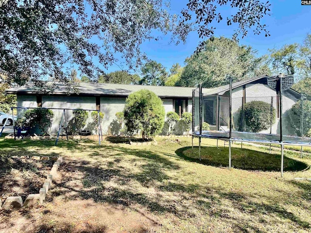 back of house featuring a lawn and a trampoline