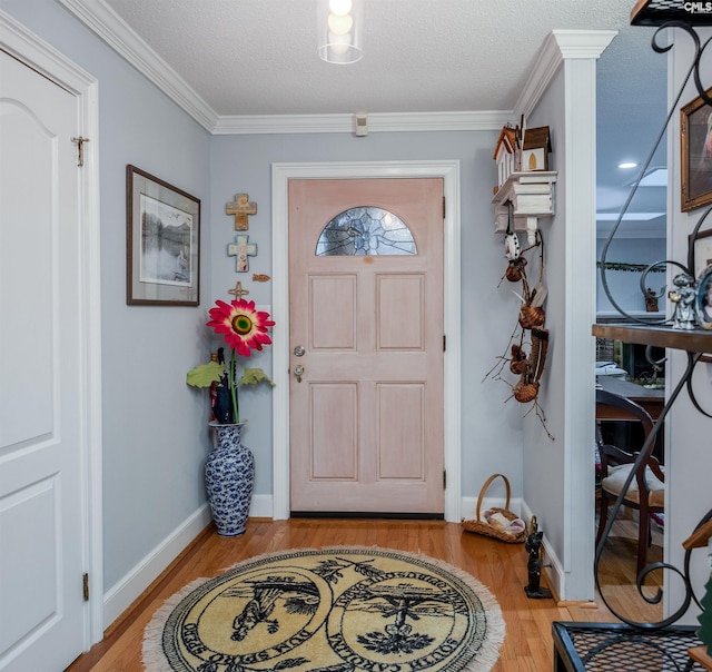 foyer entrance with a textured ceiling, light wood-type flooring, and ornamental molding