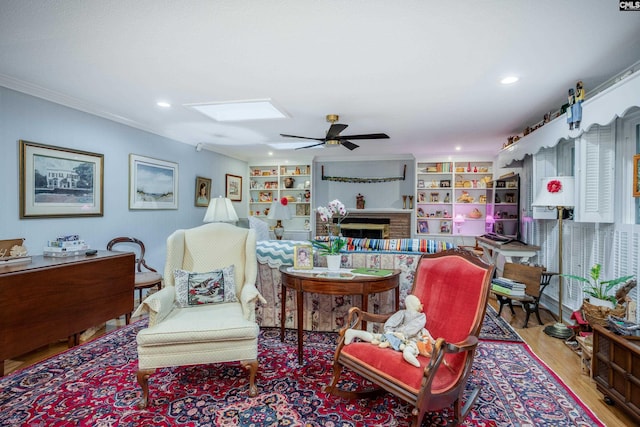 living room featuring built in shelves, light wood-type flooring, ceiling fan, and ornamental molding