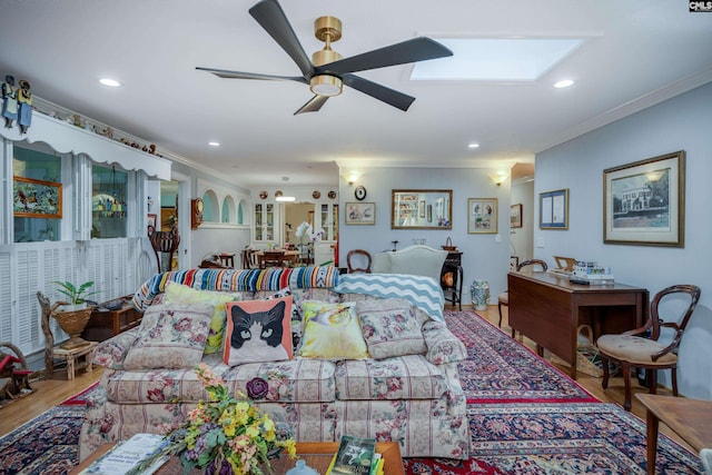 living room featuring hardwood / wood-style floors, a skylight, ceiling fan, and crown molding