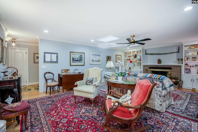 living room with built in shelves, ceiling fan, crown molding, hardwood / wood-style flooring, and a fireplace