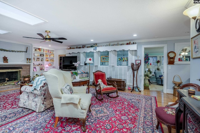 living room featuring a brick fireplace, ceiling fan, crown molding, light hardwood / wood-style flooring, and built in features