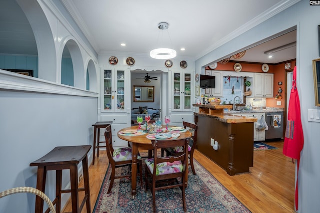 dining area featuring crown molding, sink, ceiling fan, and light hardwood / wood-style floors