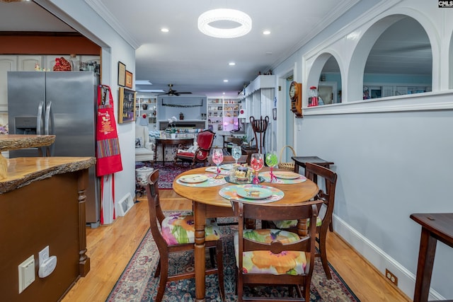 dining area with ceiling fan, light wood-type flooring, and ornamental molding