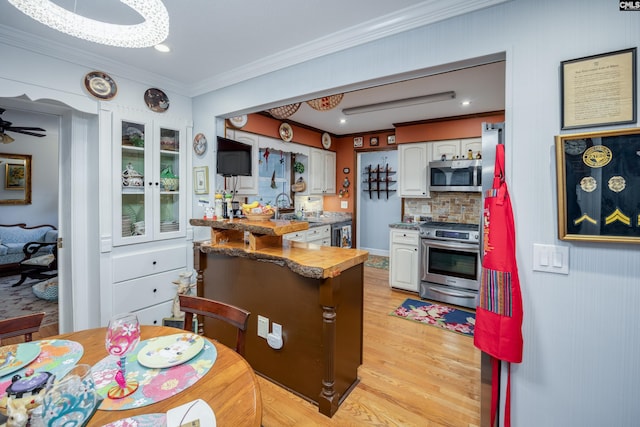 kitchen with white cabinetry, tasteful backsplash, light hardwood / wood-style flooring, appliances with stainless steel finishes, and ornamental molding