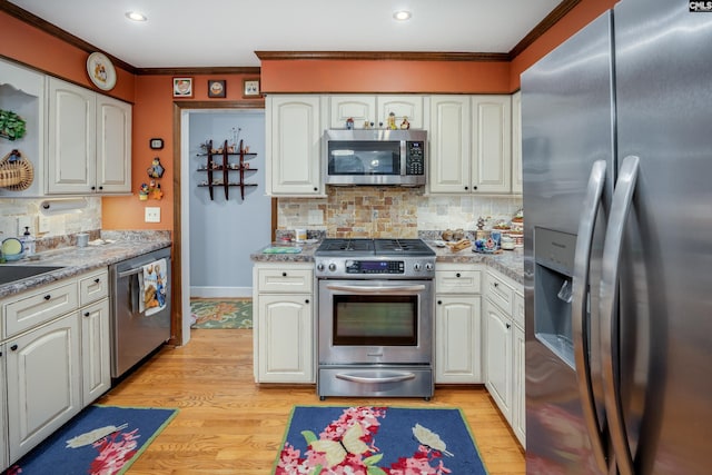 kitchen featuring white cabinets, crown molding, decorative backsplash, light wood-type flooring, and stainless steel appliances