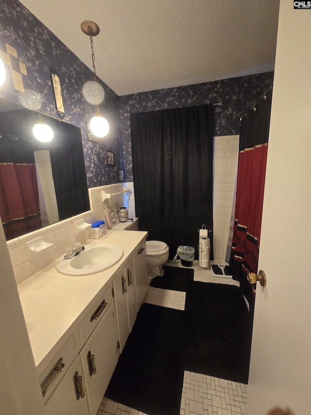 bathroom with a textured ceiling, curtained shower, vanity, and tile walls