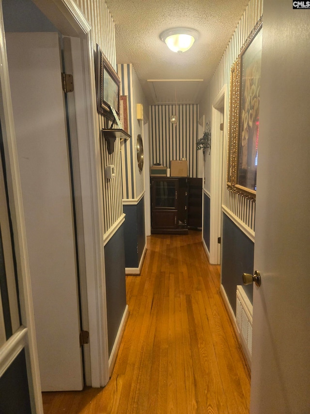 hall featuring wood-type flooring and a textured ceiling