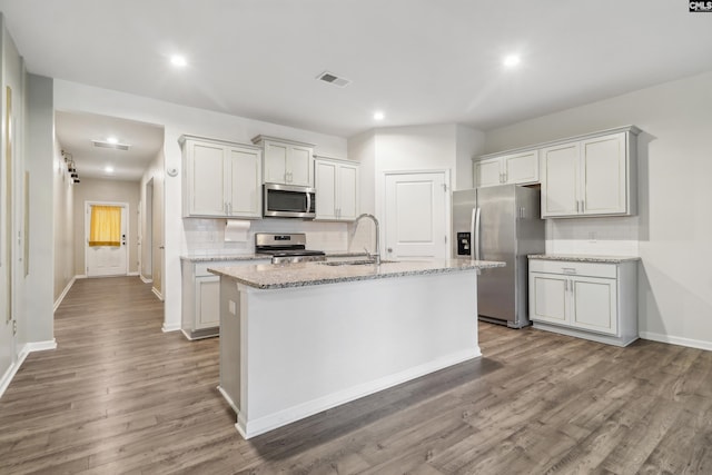 kitchen with hardwood / wood-style floors, stainless steel appliances, a center island with sink, and sink