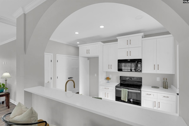 kitchen featuring white cabinetry, ornamental molding, black appliances, and hardwood / wood-style flooring