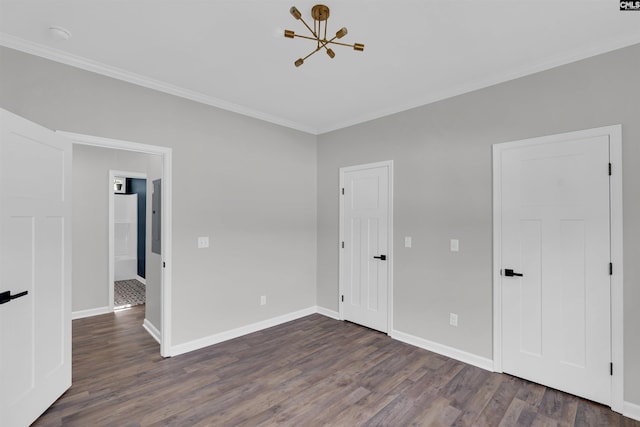 empty room with dark hardwood / wood-style floors, ornamental molding, and a notable chandelier