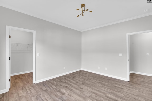 unfurnished room featuring a chandelier, crown molding, and light hardwood / wood-style flooring