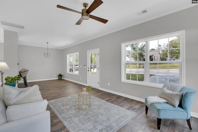 living room featuring dark wood-type flooring, a healthy amount of sunlight, and ceiling fan with notable chandelier