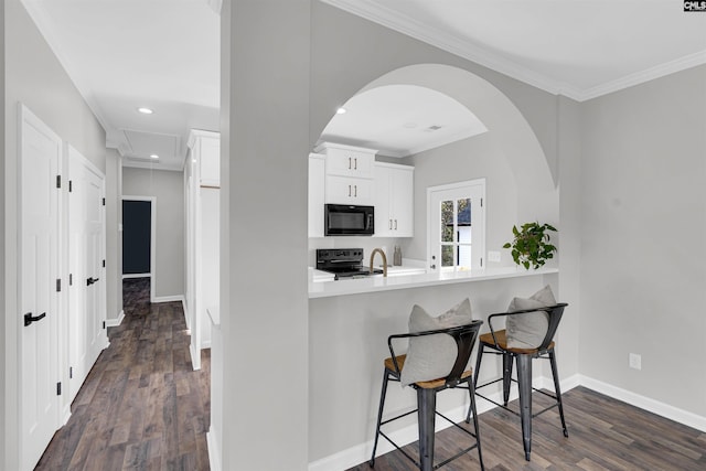 kitchen featuring dark wood-type flooring, white cabinetry, a breakfast bar area, and black appliances