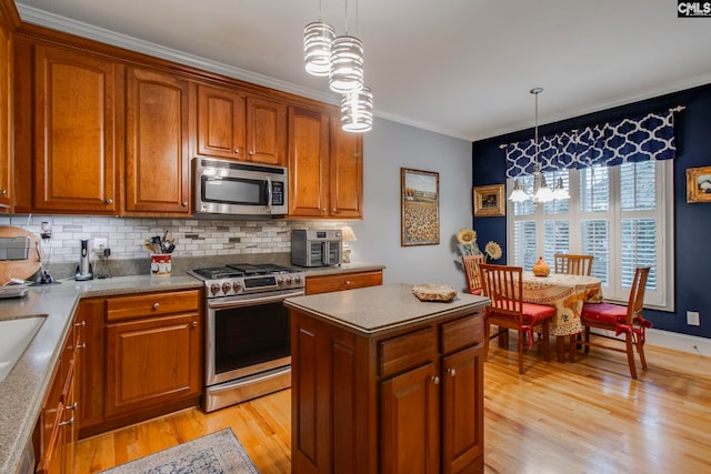 kitchen with tasteful backsplash, appliances with stainless steel finishes, decorative light fixtures, and light wood-type flooring