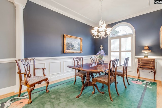 dining room featuring hardwood / wood-style flooring, crown molding, decorative columns, and an inviting chandelier