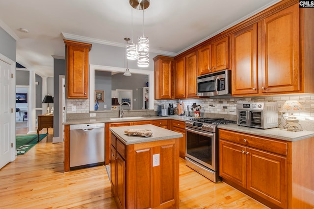 kitchen featuring a kitchen island, appliances with stainless steel finishes, pendant lighting, sink, and light hardwood / wood-style flooring