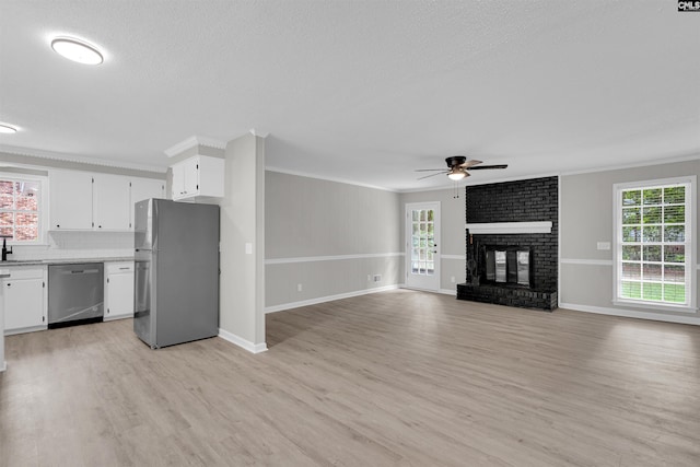 kitchen with light hardwood / wood-style flooring, white cabinets, stainless steel appliances, and a brick fireplace