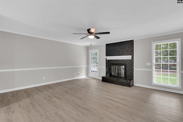 unfurnished living room with a brick fireplace, ceiling fan, crown molding, and light hardwood / wood-style flooring