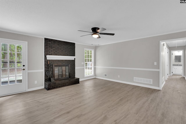 unfurnished living room featuring light hardwood / wood-style floors, a brick fireplace, ceiling fan, and crown molding