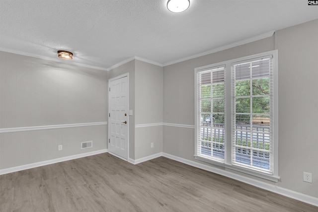 spare room featuring hardwood / wood-style flooring, ornamental molding, and a textured ceiling