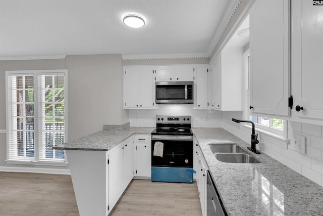 kitchen with crown molding, sink, kitchen peninsula, white cabinetry, and stainless steel appliances