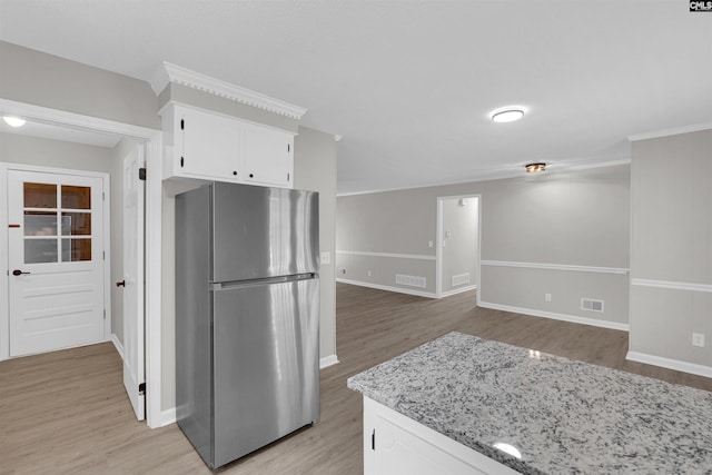 kitchen with white cabinets, light hardwood / wood-style flooring, stainless steel refrigerator, and light stone counters