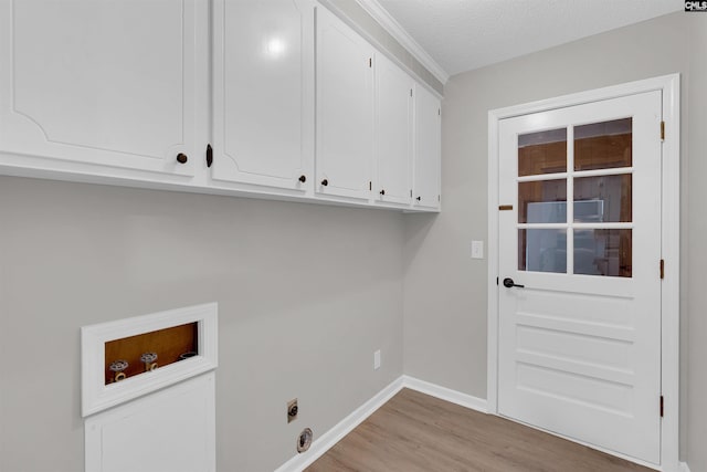 clothes washing area featuring electric dryer hookup, cabinets, light hardwood / wood-style flooring, washer hookup, and a textured ceiling