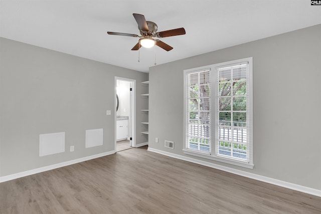 spare room featuring hardwood / wood-style flooring, ceiling fan, and built in shelves