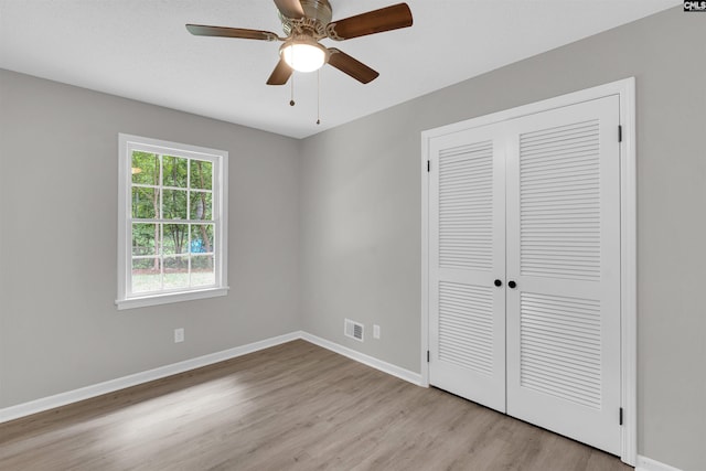 unfurnished bedroom with light wood-type flooring, a closet, and ceiling fan